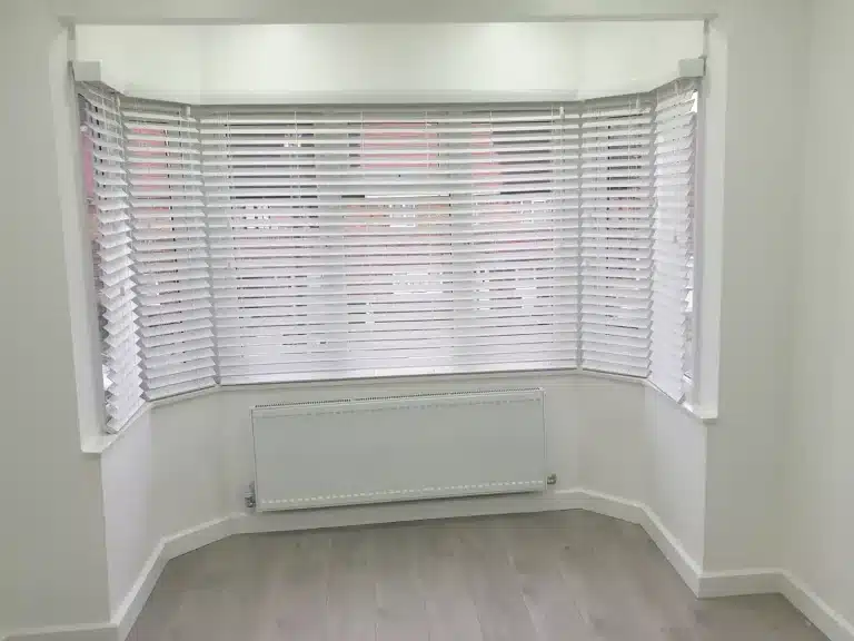 Home office shutters installed in a stylish bedroom with white wooden shutters and modern decor