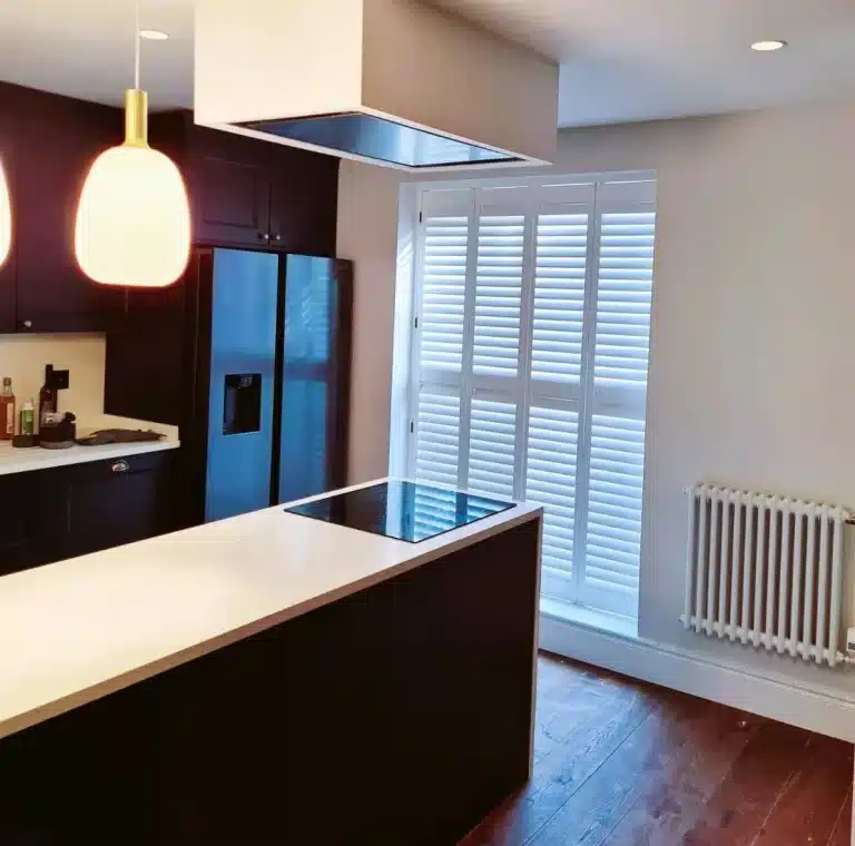 Elegant white plantation shutters on a bay window in a modern kitchen.