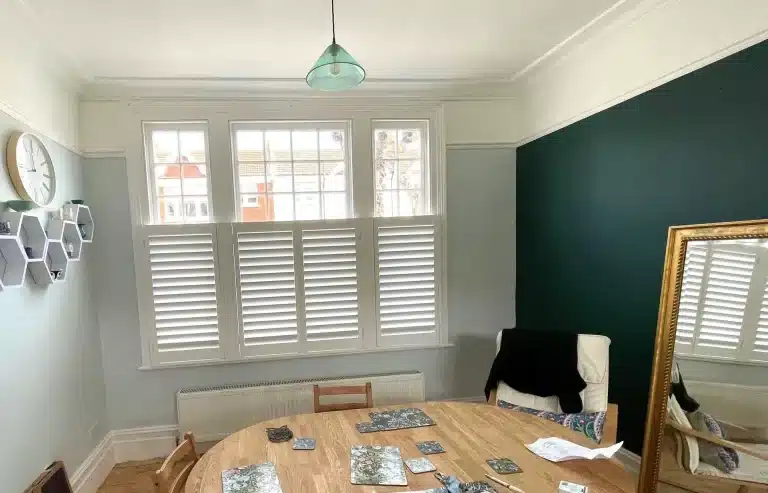 Custom window shutters from North London Shutters and Blinds enhance this dining area in a local window store.