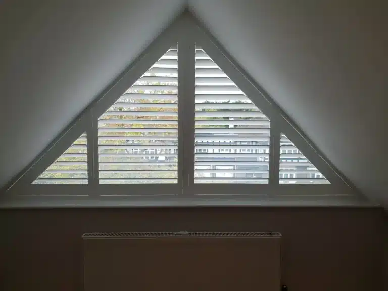 Custom wooden shutter blinds for a triangular window, providing privacy and style.