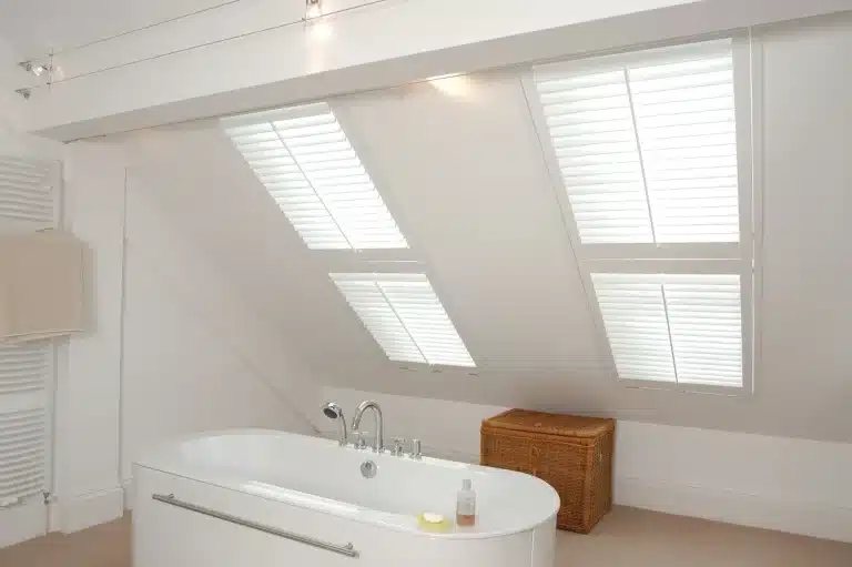 Modern bathroom featuring white shutters on windows by North London Shutters and Blinds