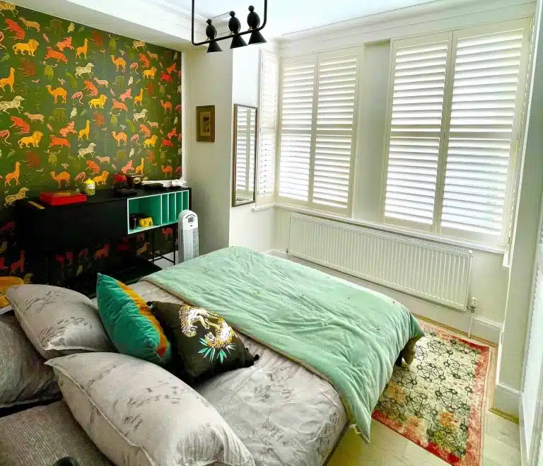 Bedroom featuring North London handcrafted window shutters with natural light streaming through.