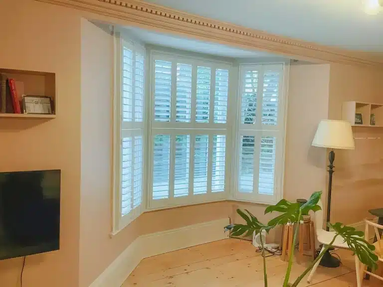 Living room featuring curtains with shutter windows by North London Shutters and Blinds