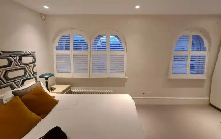 bedroom featuring North London Shutters and Blinds' waterproof blinds for shower and arched windows