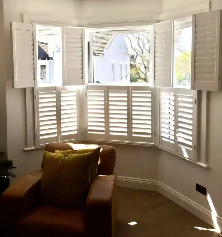 Elegant custom bay window shutters in a living room setting