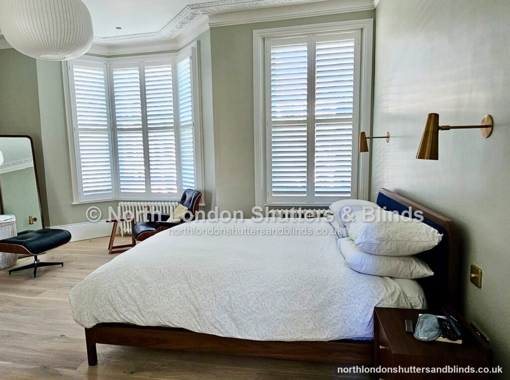White full height plantation shutters on a bay window in a bedroom by shutter fitters in Barnet, North London