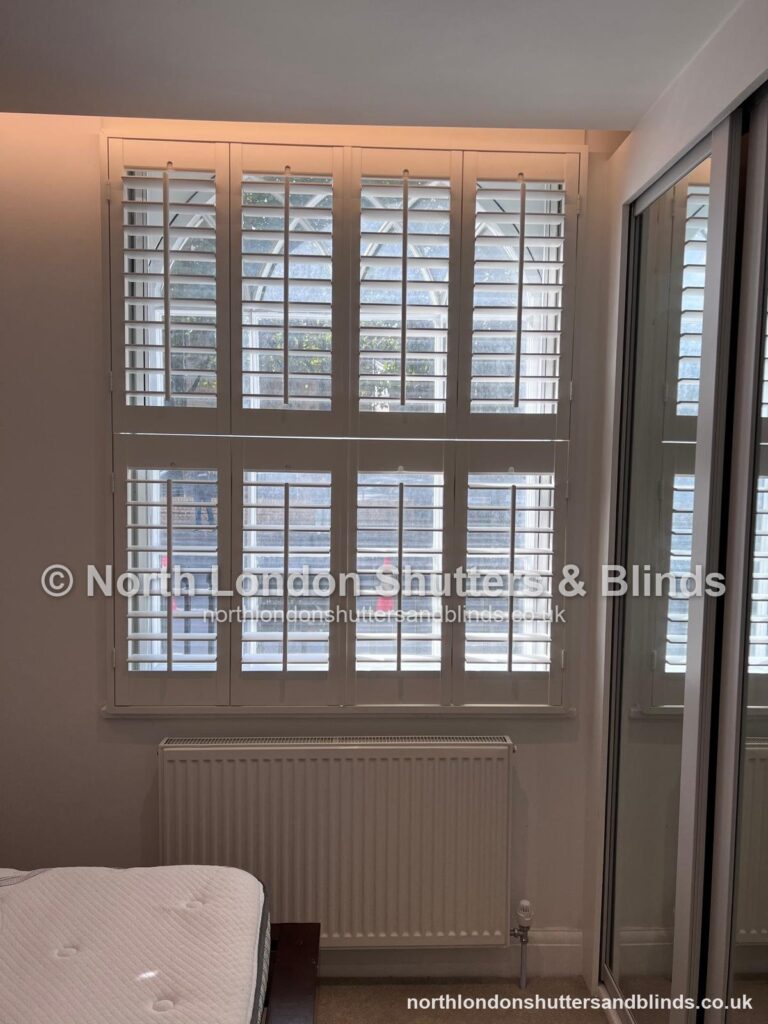 White tier-on-tier plantation shutters in a bedroom by shutter fitters in Barnet, North London
