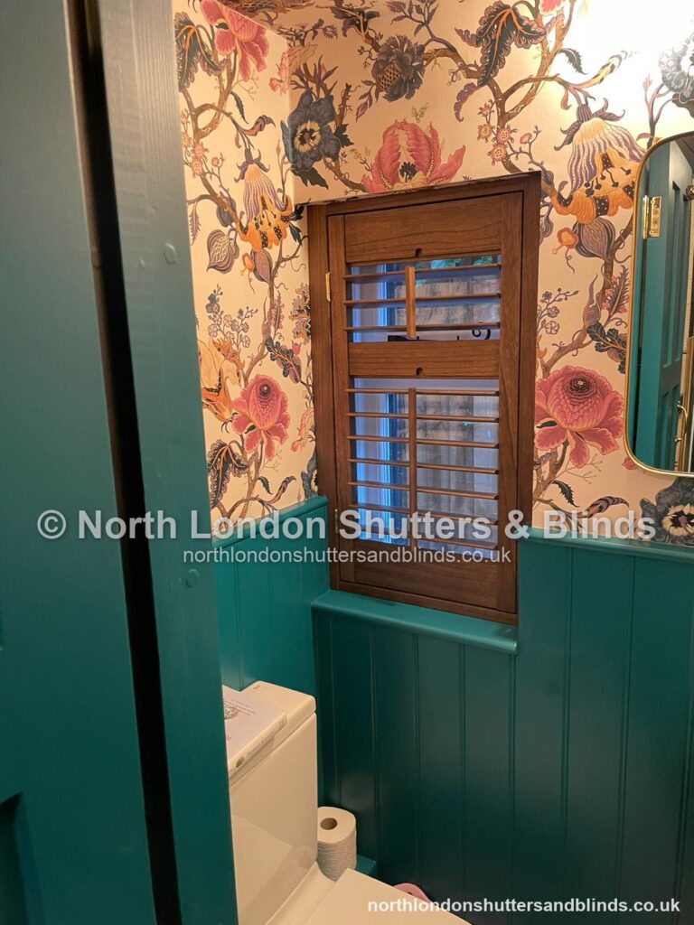 Wood-stained full height plantation shutters in a cloakroom by shutter fitters in Barnet, North London