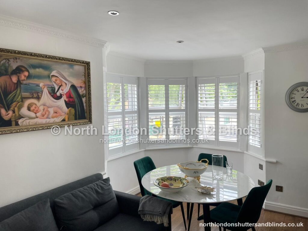 White full height plantation shutters on a bay window in a dining room by shutter fitters in Barnet, North London