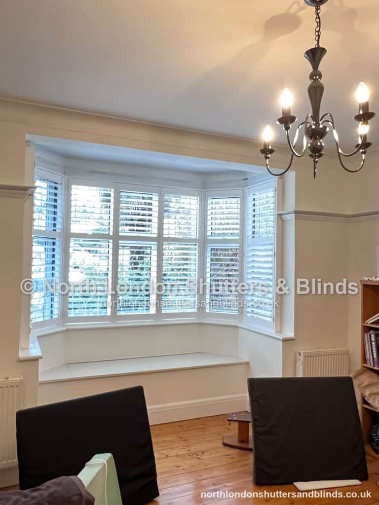 White full height plantation shutters on a bay window in a dining room by shutter fitters in Barnet, North London