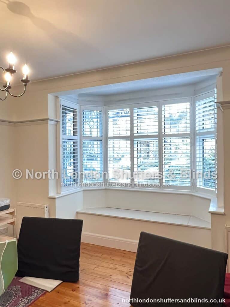 White full height plantation shutters on a bay window in a dining room by shutter fitters in Barnet, North London