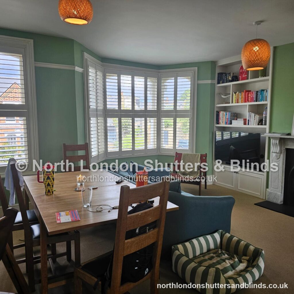 White tier-on-tier plantation shutters on a bay window in a dining room by shutter fitters in Barnet, North London