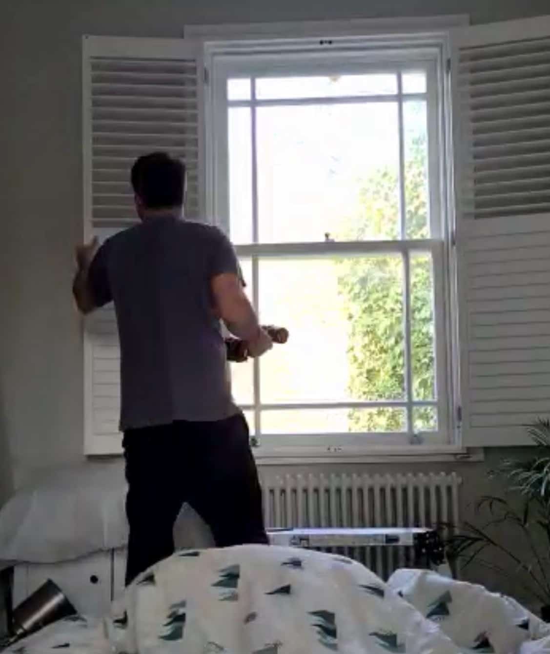Our fitter installing wooden shutters on a sash window in a North London home