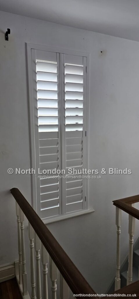 White full height plantation shutters on a staircase window on a landing by shutter fitters in Barnet, North London