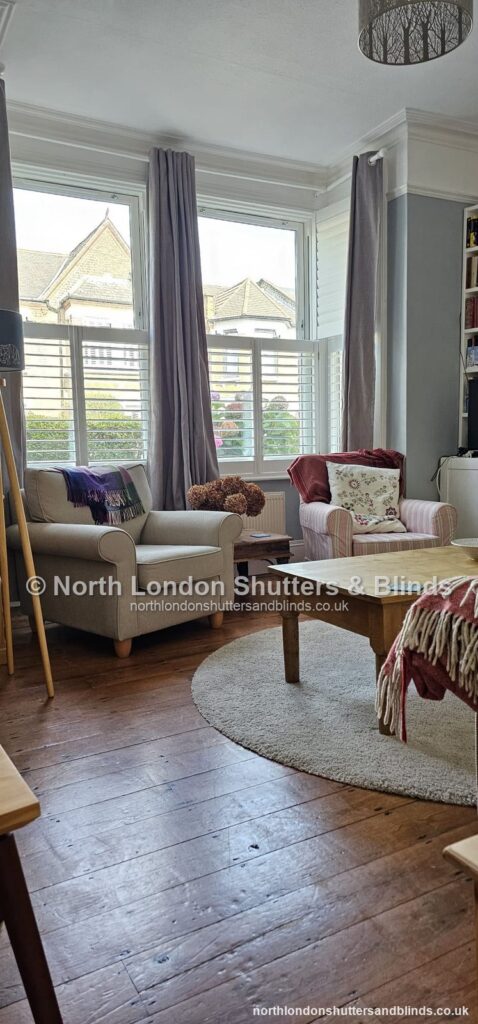 White café style plantation shutters on a bay window in a living room by shutter fitters in Barnet, North London