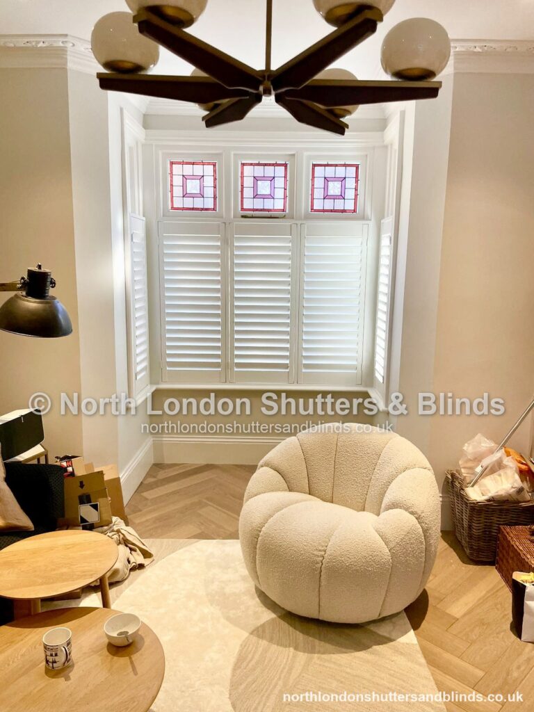 White café style plantation shutters on a bay window in a living room by shutter fitters in Barnet, North London