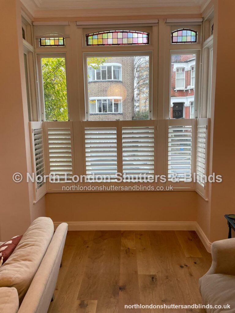 White café style plantation shutters on a bay window in a living room by shutter fitters in Barnet, North London
