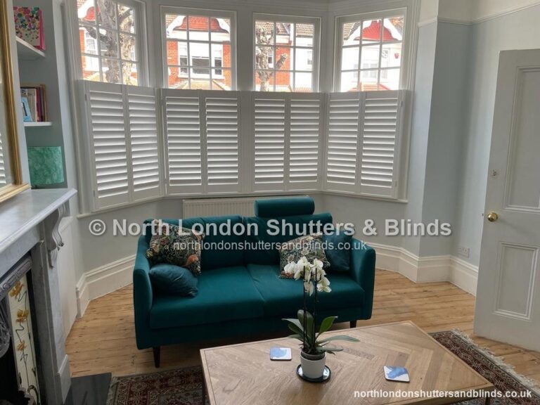 White café style plantation shutters on a bay window in a living room by shutter fitters in Barnet, North London