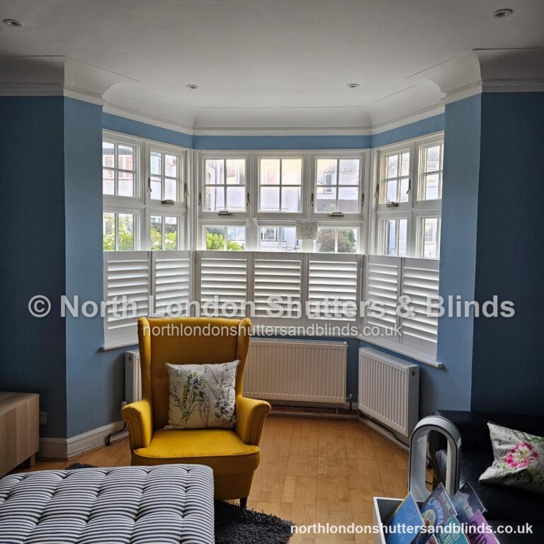 White café style plantation shutters on a bay window in a living room by shutter fitters in Barnet, North London
