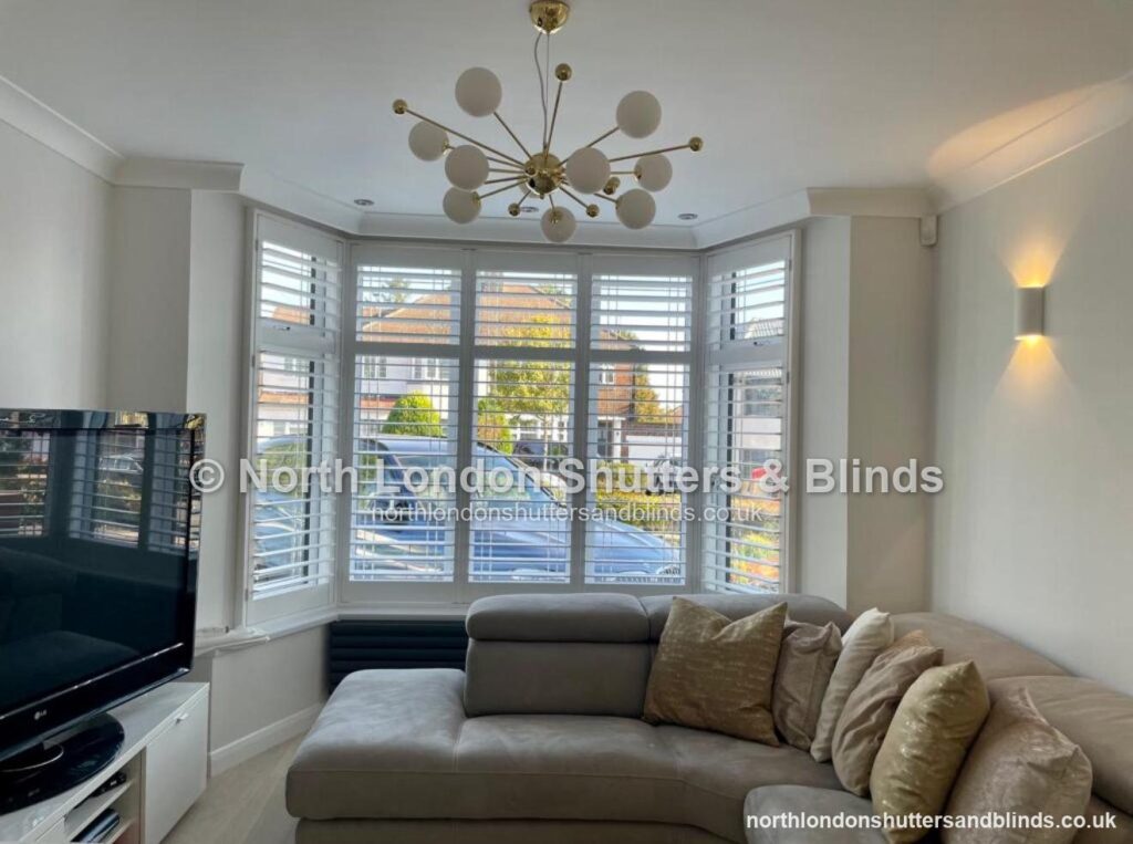 White full height plantation shutters on a bay window in a living room by shutter fitters in Barnet, North London