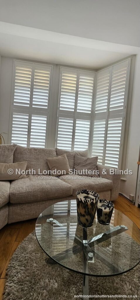 White full height plantation shutters on a bay window in a living room by shutter fitters in Barnet, North London