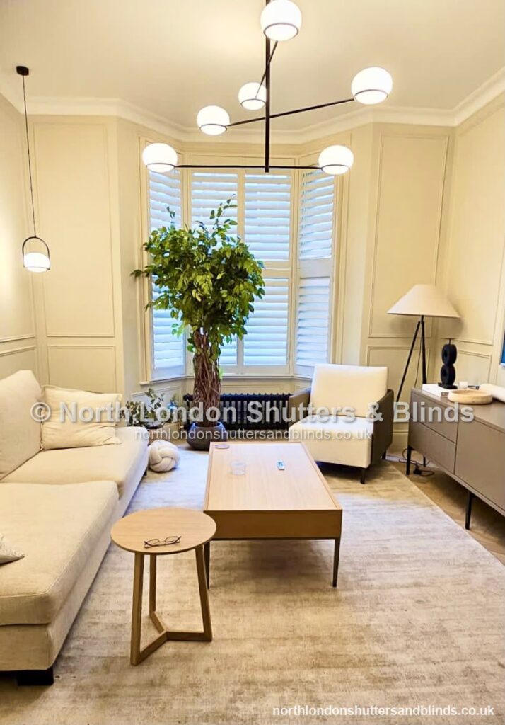 White full height plantation shutters on a bay window in a living room by shutter fitters in Barnet, North London