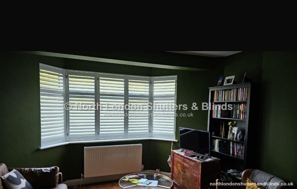 White full height plantation shutters on a bay window in a living room by shutter fitters in Barnet, North London