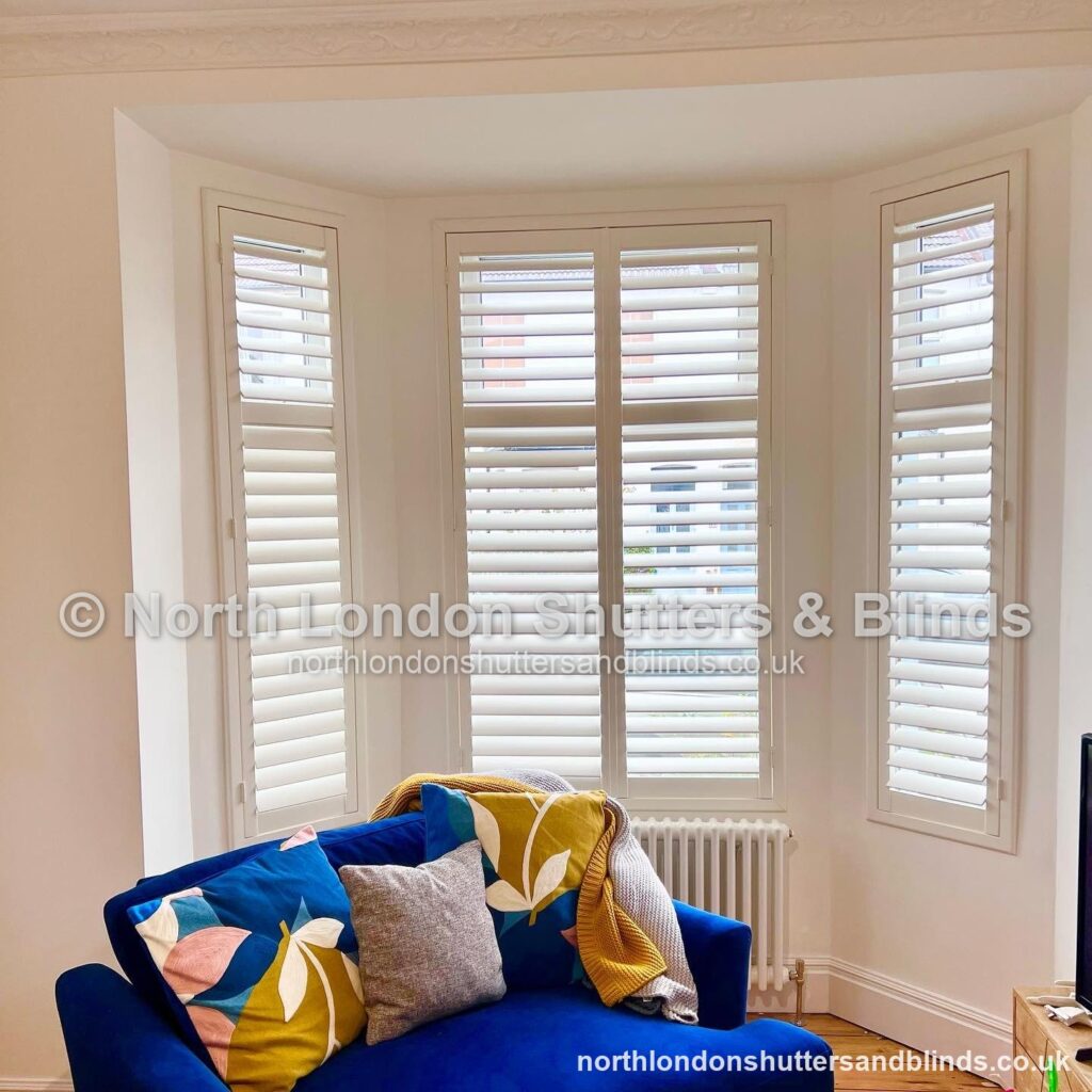 White full height plantation shutters on a bay window in a living room by shutter fitters in Barnet, North London