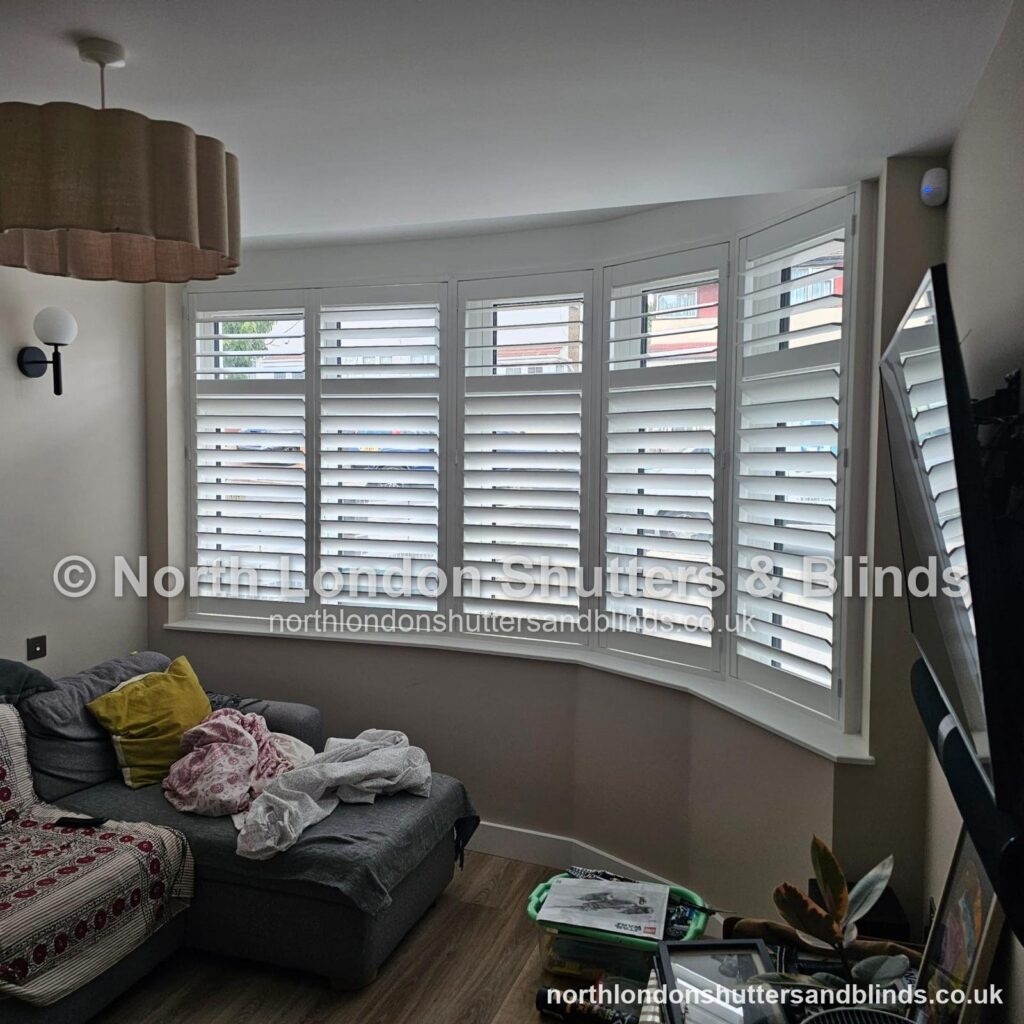 White full height plantation shutters on a bay window in a living room by shutter fitters in Barnet, North London