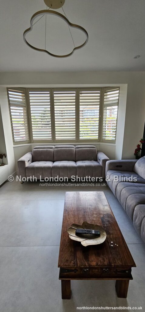 White full height plantation shutters on a bay window in a living room by shutter fitters in Barnet, North London
