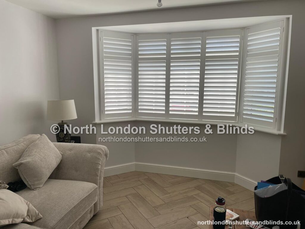 White full height plantation shutters on a bay window in a living room by shutter fitters in Barnet, North London