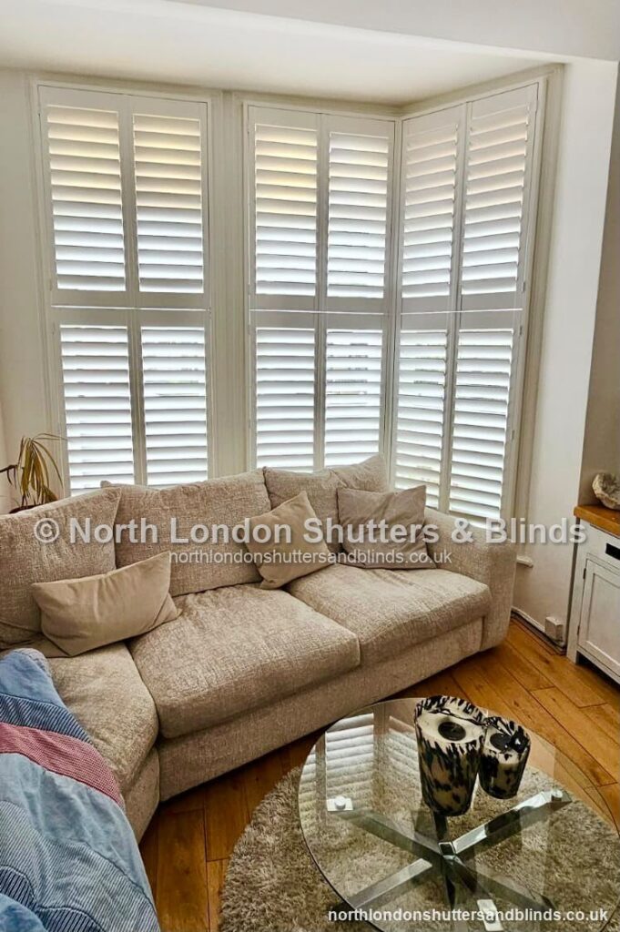White full height plantation shutters on a bay window in a living room by shutter fitters in Barnet, North London