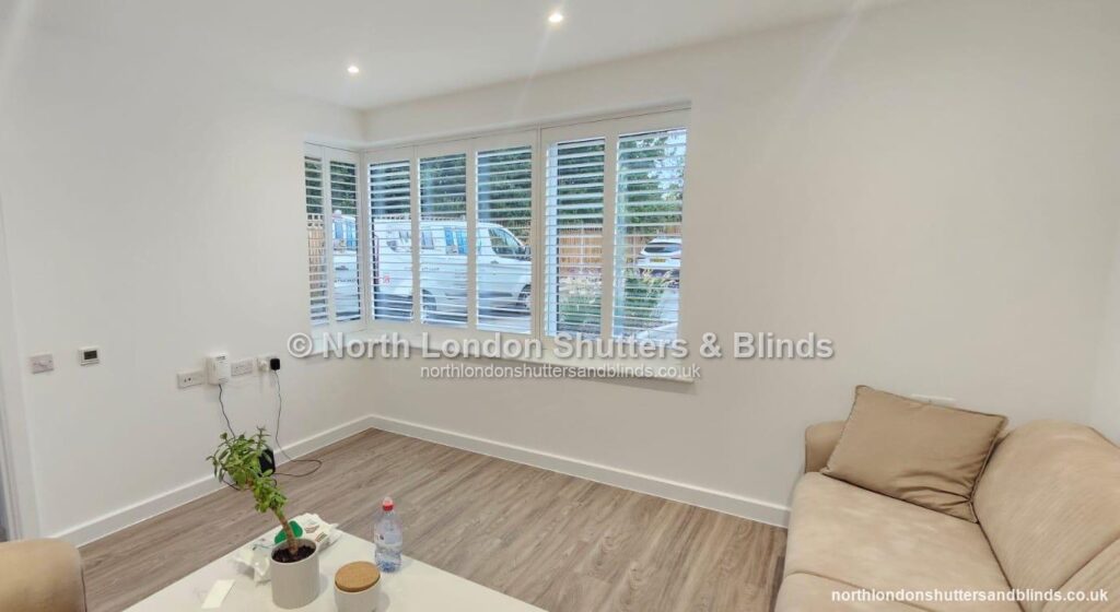 White full height plantation shutters on a corner window in a living room by shutter fitters in Barnet, North London