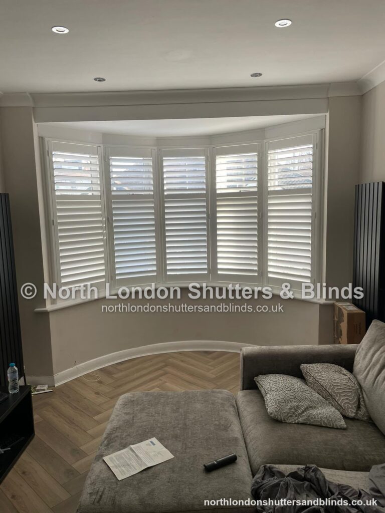 White full height plantation shutters on a curved bay window in a living room by shutter fitters in Barnet, North London
