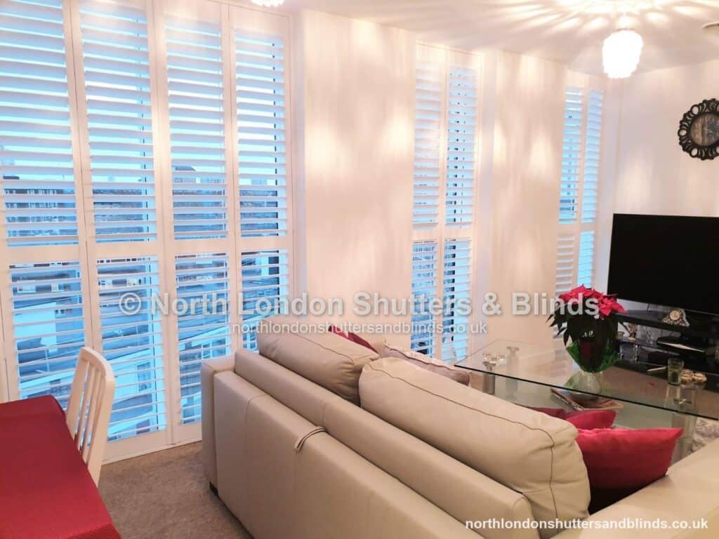 White full height plantation shutters on floor-to-ceiling windows in a living room by shutter fitters in Barnet, North London