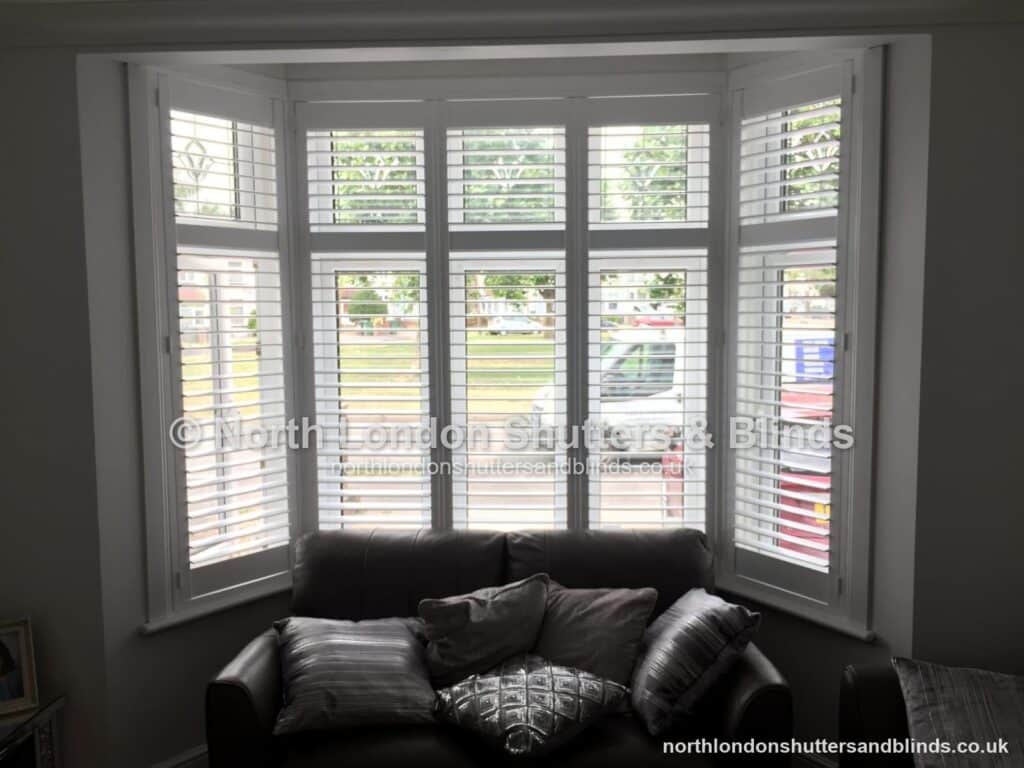 White full height plantation shutters on a square bay window in a living room by shutter fitters in Barnet, North London