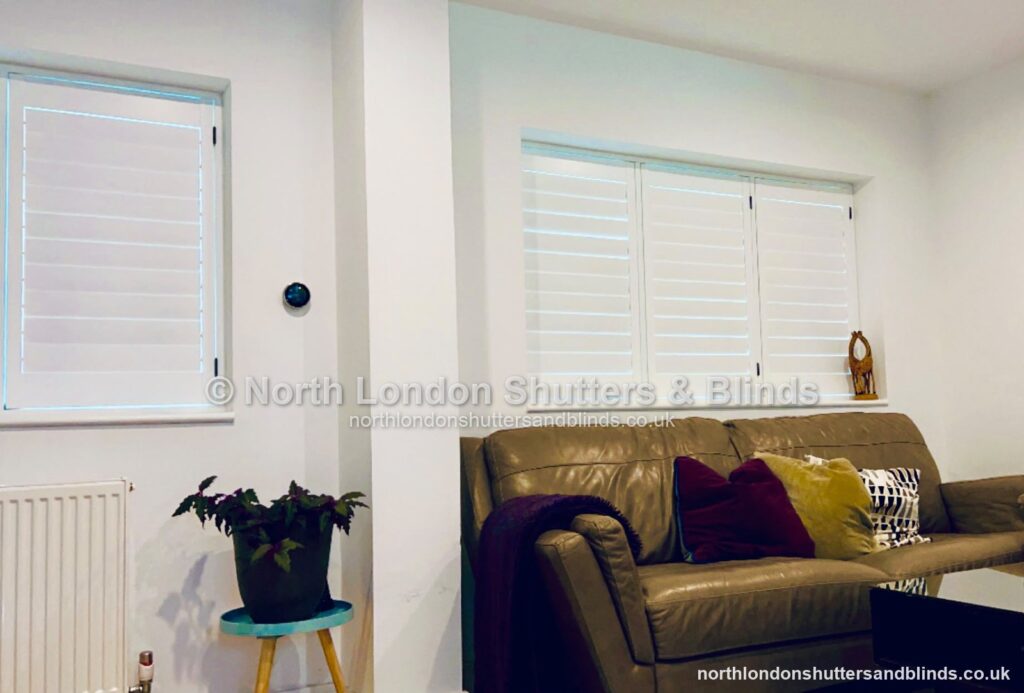 White full height plantation shutters on two alcove windows in a living room by shutter fitters in Barnet, North London