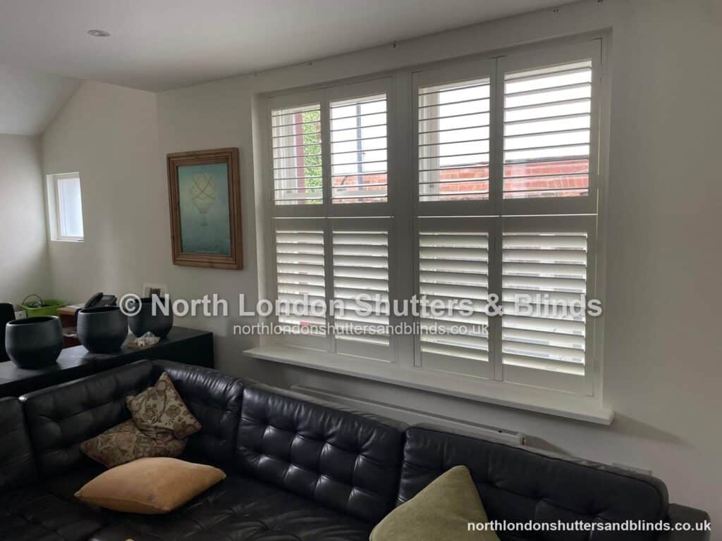White tier-on-tier plantation shutters in a living room by shutter fitters in Barnet, North London