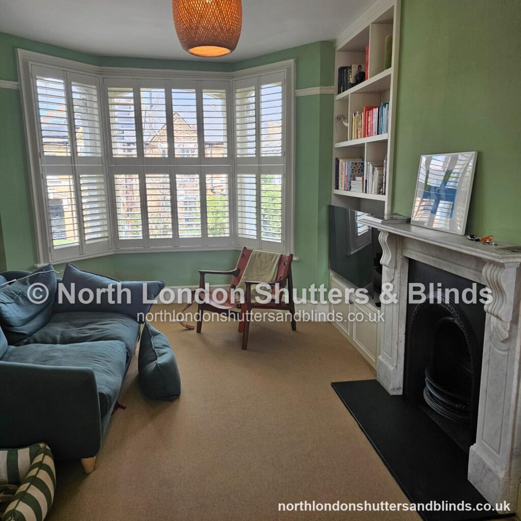 White tier-on-tier plantation shutters on a Victorian bay window in a living room by shutter fitters in Barnet, North London