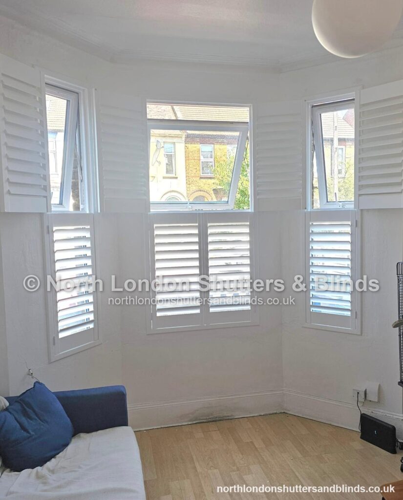 White tier-on-tier plantation shutters on a bay window in a living room by shutter fitters in Barnet, North London
