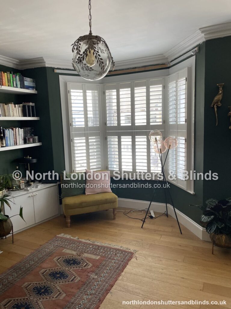 White tier-on-tier plantation shutters on a bay window in a living room by shutter fitters in Barnet, North London