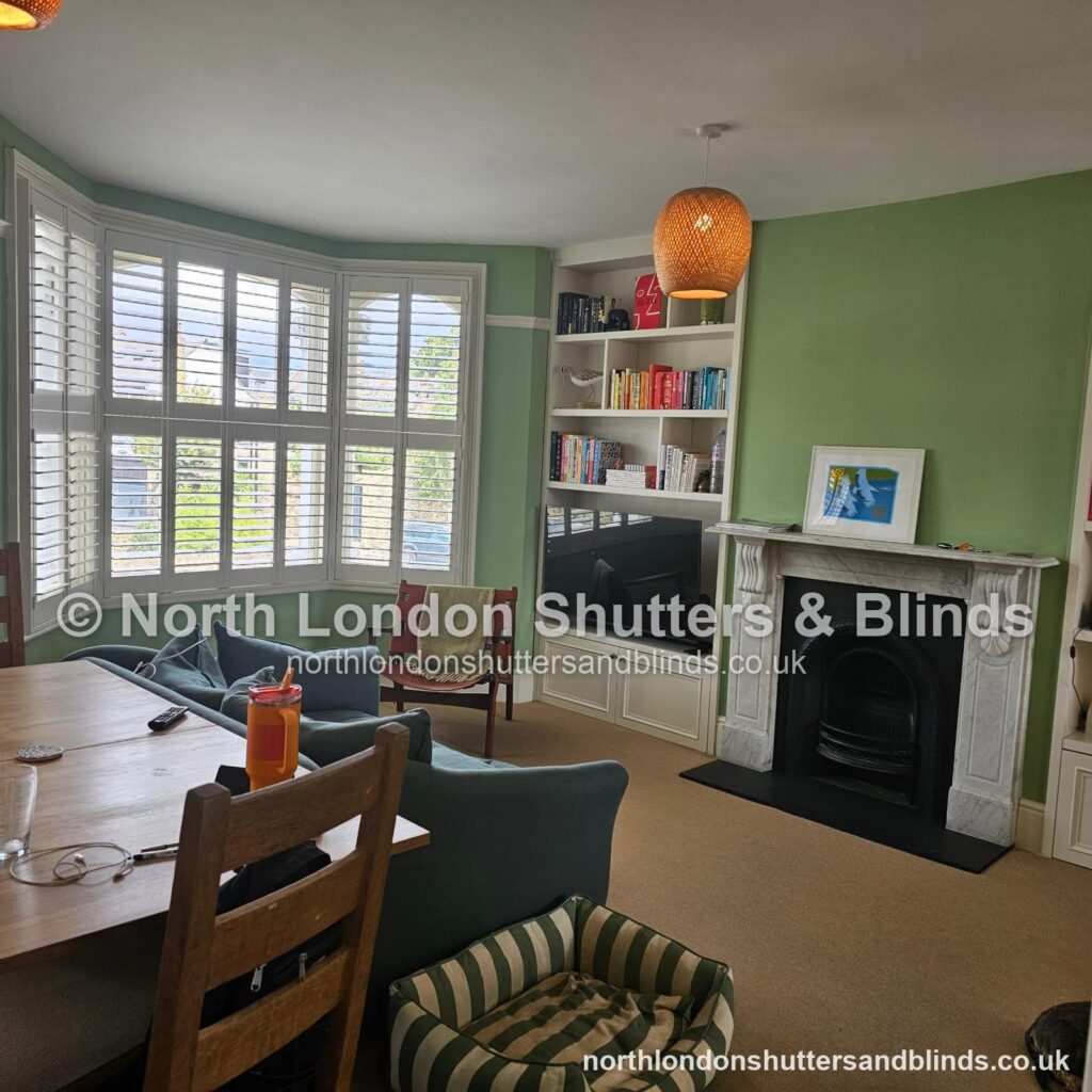 White tier-on-tier plantation shutters on a bay window in a living room by shutter fitters in Barnet, North London