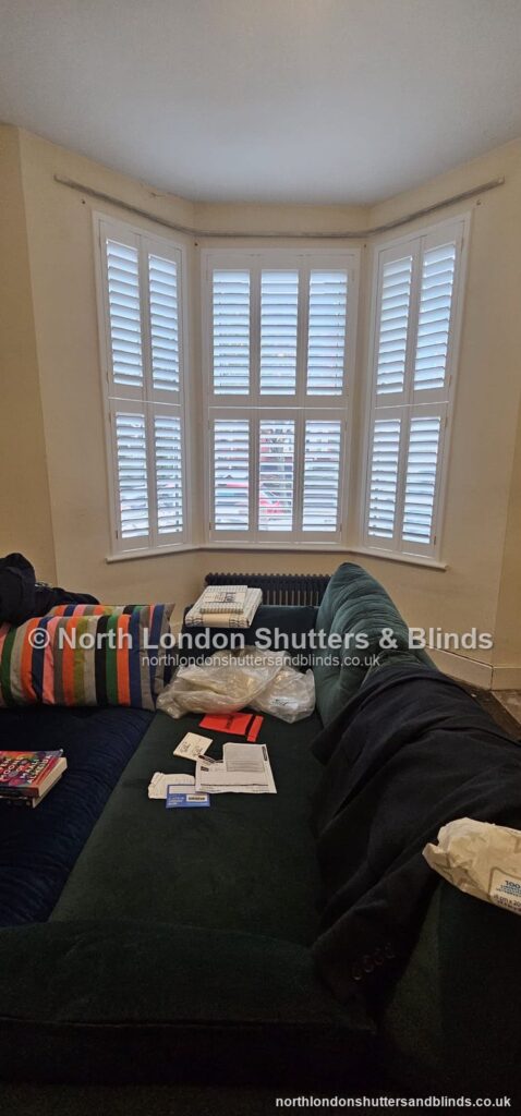White tier-on-tier plantation shutters on a bay window in a living room by shutter fitters in Barnet, North London