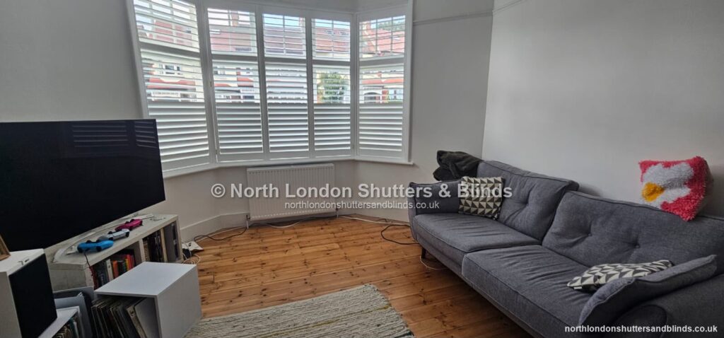 White tier-on-tier plantation shutters on a bay window in a living room by shutter fitters in Barnet, North London