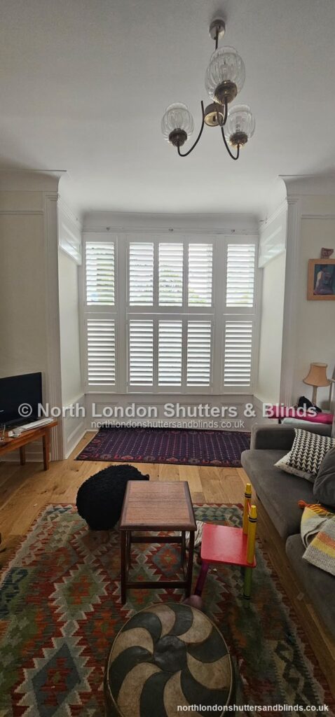 White tier-on-tier plantation shutters on a bay window in a living room by shutter fitters in Barnet, North London