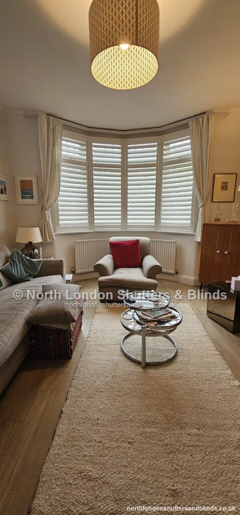 White tier-on-tier plantation shutters on a bay window in a living room by shutter fitters in Barnet, North London