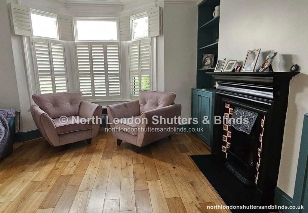 White tier-on-tier plantation shutters on a bay window in a living room by shutter fitters in Barnet, North London