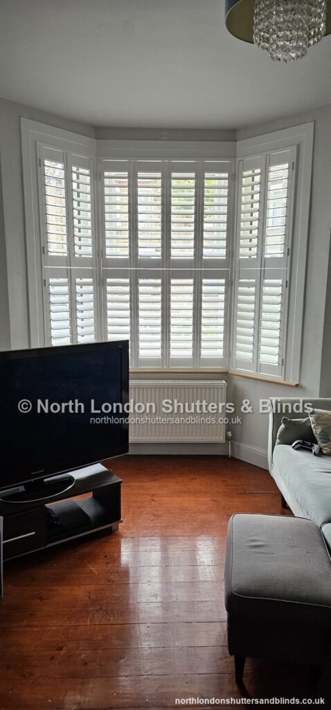 White tier-on-tier plantation shutters on a bay window in a living room by shutter fitters in Barnet, North London