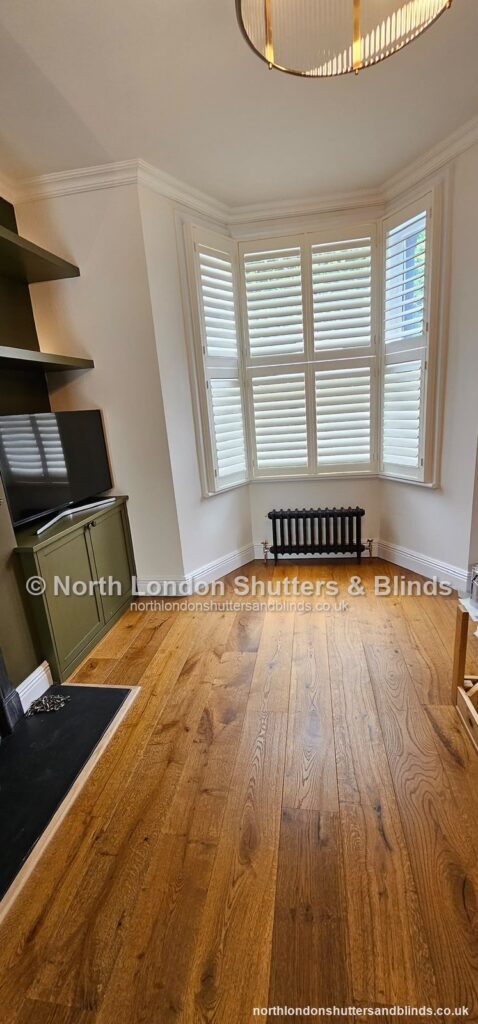 White tier-on-tier plantation shutters on a bay window in a living room by shutter fitters in Barnet, North London