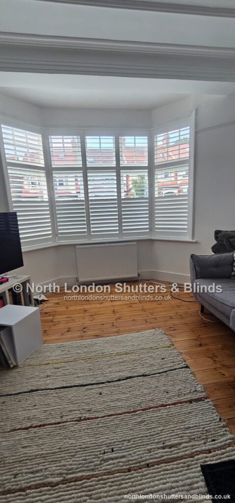 White tier-on-tier plantation shutters on a bay window in a living room by shutter fitters in Barnet, North London